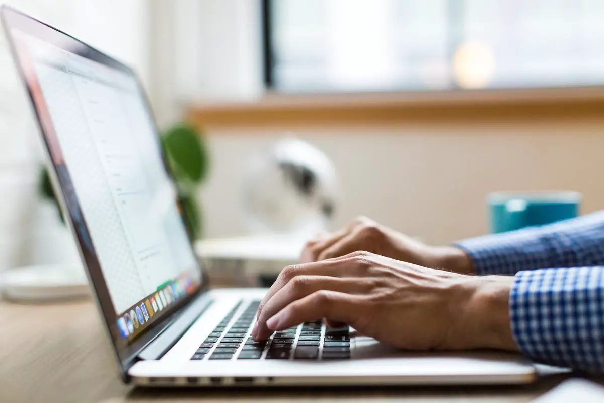 Image of a person typing on a laptop while sitting at a coffee shop, representing freelance blogging